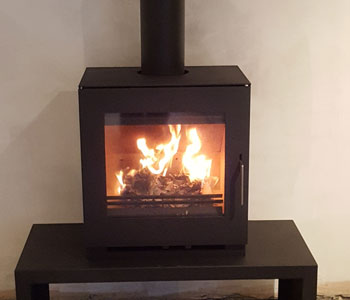 Westfire Uniq 23 Wood Burning Stove - with 50mm block base and table stand installation with twin wall, thermally insulated chimney system and black slate hearth in Bookham, near Leatherhead, Surrey.